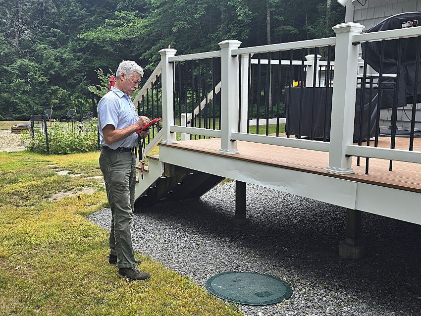 Gray-hair man with clipboard inspecting septic system hole