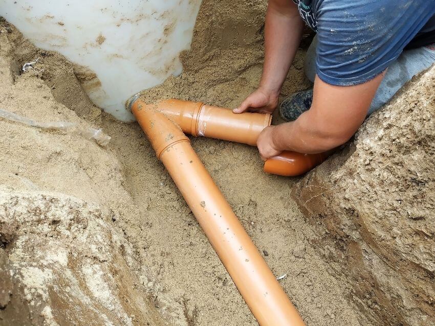 Closeup of man's arms and hands around a pipe in culvert