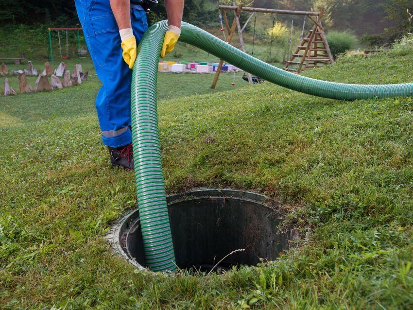 Closeup of man's hands holding hose into septic tank