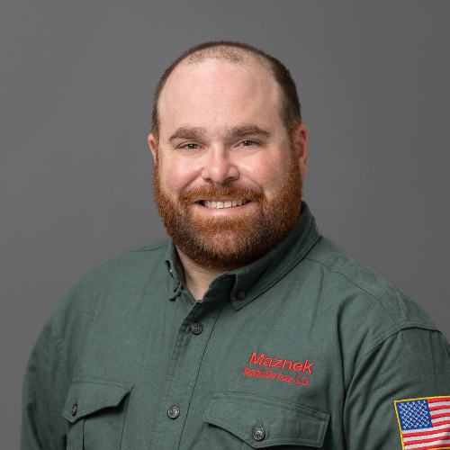 Man with beard and mustache wearing green work shirt with American flag patch on arm