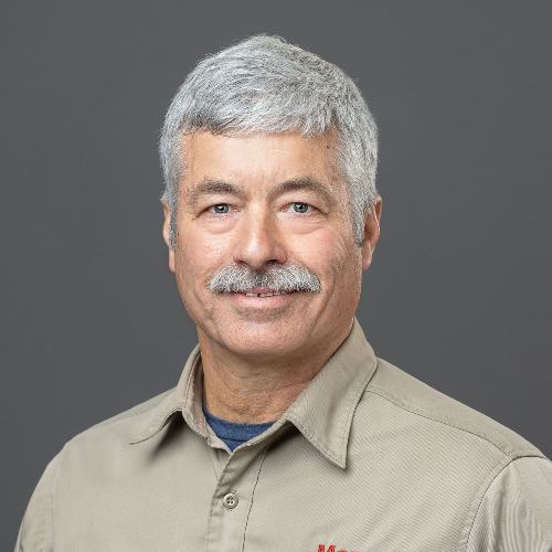 Gray-haired man wearing tan workshirt