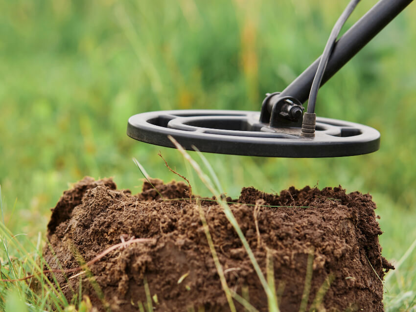 Large black metal detector hovering over pile of dirt