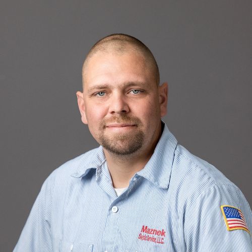 Man with mustache and beard wearing blue button-down shirt with American flag on arm sleeve